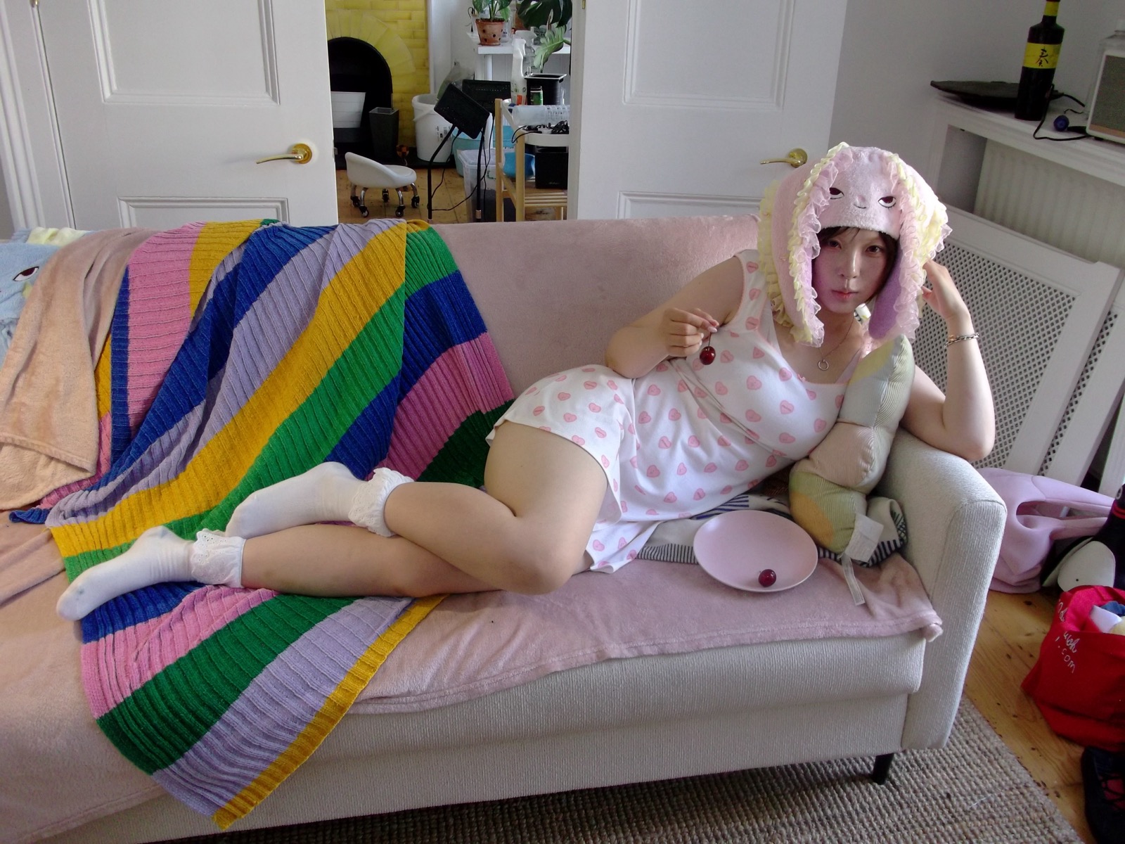 Model wearing the pink HOHOMIE bunny cap while reclining on a pastel couch